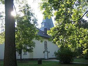 St. Johannes der Täufer Kirche Kirche umgeben von Bäumen im Sonnenlicht.