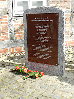 Gedenkstein Gedenkstein mit Inschrift zur Erinnerung an Todesmärsche durch Winsen (Aller), Blumen davor.